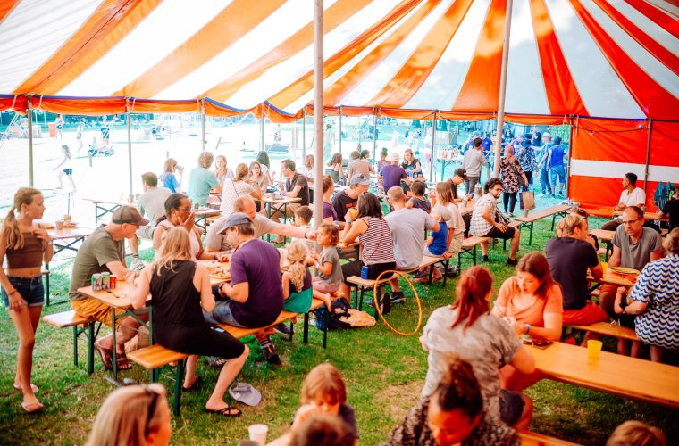 Buurtbewoners kamperen samen aan de Strandweg in Almere Haven, met tenten en een recreatieve sfeer.